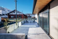 建物をL字でぐるりと囲んだタイルデッキは、BBQや日光浴など、アウトドアリビングとして大活躍。外と室内をシームレスにつなぎ、リゾートのような開放感を味わえる。ワンちゃんのお散歩にも最適【tact design firm】
