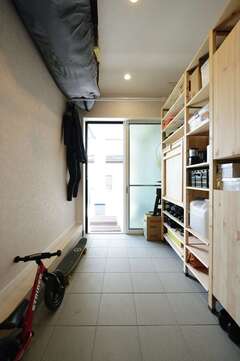 ご主人の念願の土間スペースはサーフボードを置けるように３m以上の長さを確保。駐車場から直接出入りできる。壁面の棚は市販の家具をご主人自ら組み立ててコストダウン