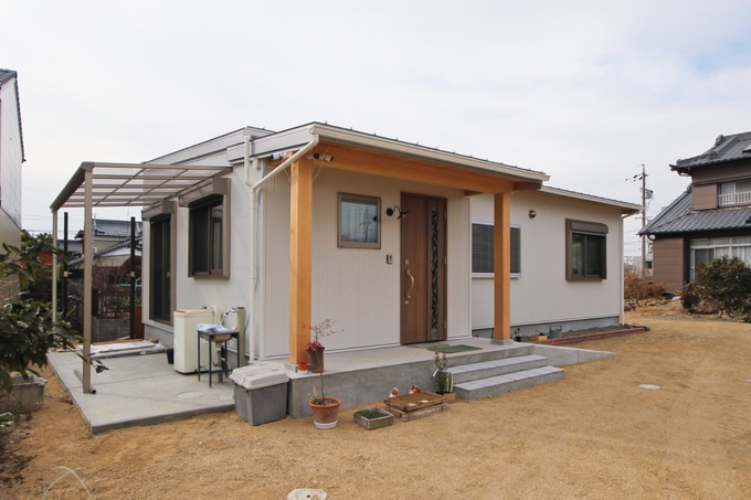 シンプルでコンパクトな平屋建築の外観。木材を使ったエントランスが自然な温かみを添え、穏やかな住宅街に調和している。