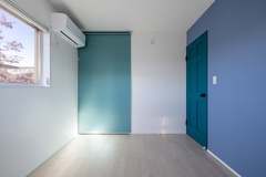 壁に鮮やかなブルーを配した子ども部屋。シンプルなインテリアが広がりを感じさせ、明るく開放的な空間を演出している。