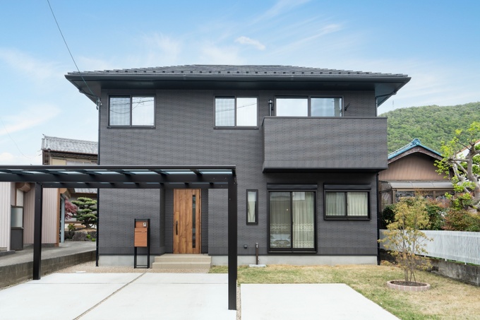 モダンなデザインが印象的な二階建て住宅。黒を基調としたタイル外壁がシックで落ち着いた雰囲気を演出している。