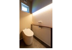 落ち着いた色調でまとめられたトイレ空間。間接照明が柔らかい雰囲気を演出しており、シンプルながらも洗練されたデザインである。【三交不動産】