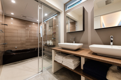 ツーボウルの洗面カウンターとガラス張りの浴室というリクエストを叶えたサニタリー空間。洗面化粧台もオーダーメイドでこだわりを具現化