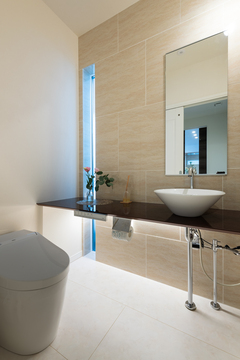 ゆとりの広さを確保したパウダールーム。アクセントタイルや特注カウンター、間接照明でスタイリッシュに仕上げている