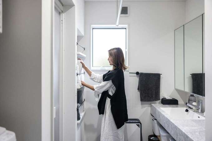 洗面脱衣所兼ランドリールーム。奥さまの希望を叶えたタオルニッチは、奥行きやバーの位置など綿密に計算。洗面台の大理石調のカウンタートップは幅を広くし、洗濯物を畳む作業台としても活用する