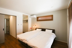 広々とした寝室は、シンプルで落ち着いたインテリアが施されている。心地よい光が差し込む窓があり、リラックスできる空間である。