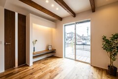 家族が安心して暮らせる住環境を追求し、壁には調湿・消臭効果のある焼成ホタテしっくい、床には木の風合いを生かしたムクフローリングを採用した。3本の見せ梁や造作のTVカウンターがこだわりのポイントだ。