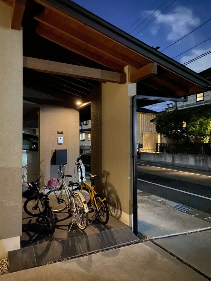家の一部として設計されたアプローチ内に駐輪場を計画。道路から直接アクセスでき、夕暮れ時の雰囲気が落ち着いた印象を与える。