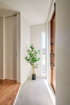 明るい自然光が差し込む玄関。シンプルなインテリアと観葉植物が落ち着いた雰囲気を演出している。