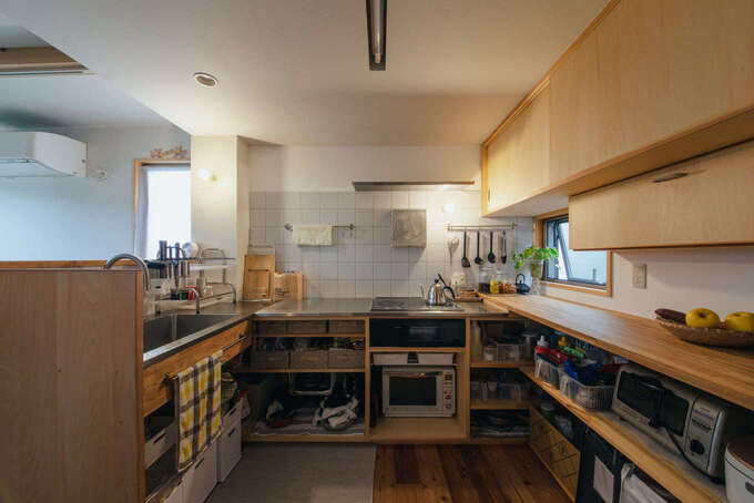 キッチン下部はオープンラックにして、カゴを使って収納。扉つき造作収納には食器類を納めている。「事前に皿やグラスのサイズをお伝えしたら、ジャストサイズに仕上がって驚きました」と奥さまは笑う。スペースを無駄にせず、シンプルに暮らせる秘訣がここに