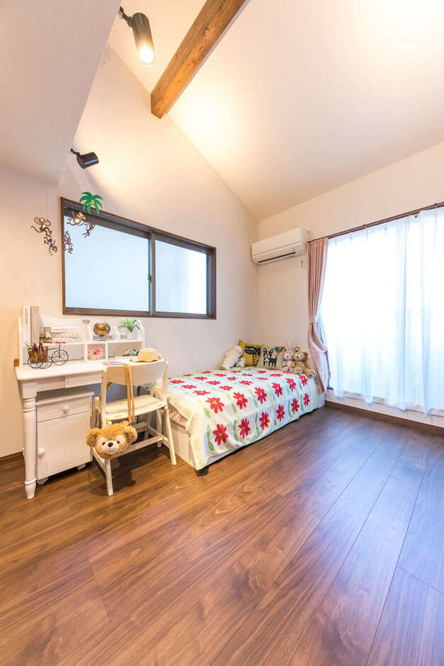 明るく開放的な子ども部屋。勾配天井でゆったりと過ごせる空間に。床材とトーンを揃えた見せ梁がアクセントになっている
