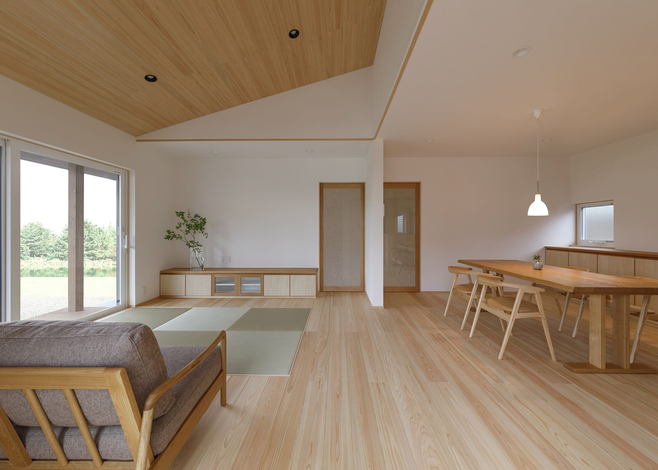 勾配天井にもヒノキが張られ、大らかさで清々しい空間が完成。調和するように設けられた畳スペースが、和の落ち着きを添えている。テレビボードも造作。同社でよく採用される框戸は、二重のガラスの間に織布がはさまれたもので、光と気配を穏やかに透過させる