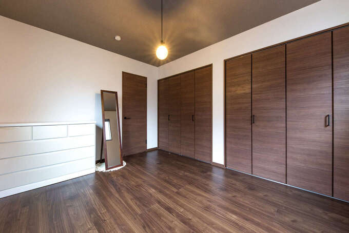 夫婦の寝室はシンプルに。壁一面はクローゼットにして収納スペースを確保。天井にはアクセントクロスを用いてシックに整えた