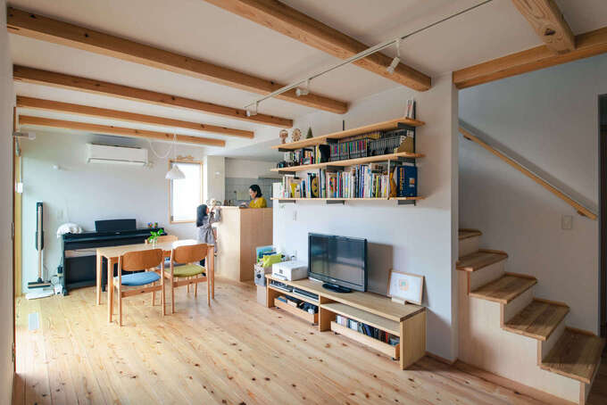 床を覆うスギの柔らかな感触が心地よいリビング。中央にある階段がLDKと水回りを分け、行き止まりのない暮らしの動線を形にしている。テレビ上の本棚も建築時に造作してもらったもの