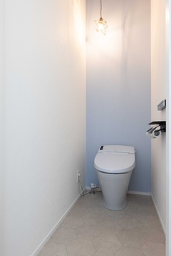 シンプルで清潔感のあるトイレ空間。柔らかなライトが上部に灯り、落ち着いた雰囲気を演出している。