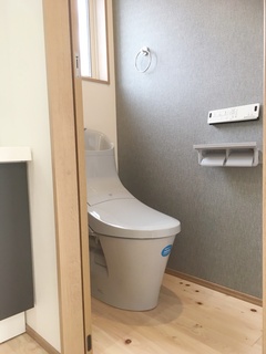 コンパクトで機能的なトイレ空間。床材が上質な雰囲気を醸し出し、グレーの壁紙が落ち着きを与えている。