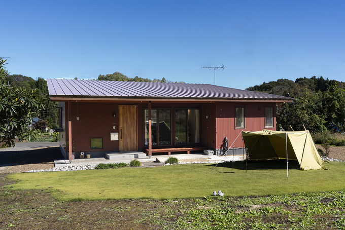 広々とした庭に面したシンプルで美しい平屋の外観が印象的な住宅。緑に囲まれた自然豊かな環境に佇む。