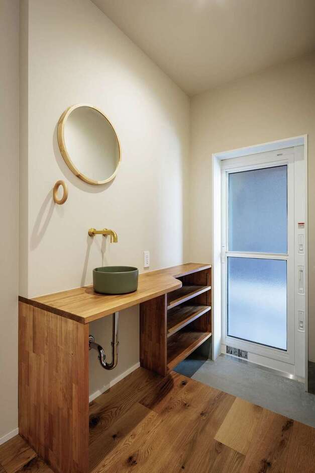 玄関の通り土間からも外からもアクセスできる造作の手洗いコーナー。真鍮の水栓と丸い鏡がおしゃれ