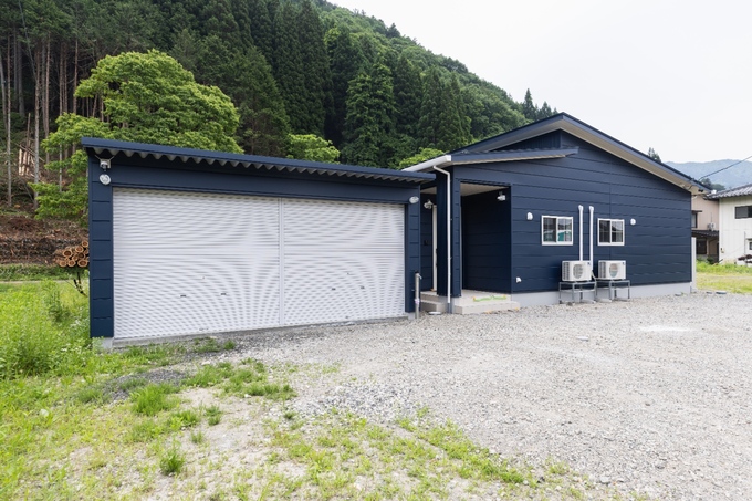 緑豊かな自然に囲まれた住宅の外観。広いガレージと機能的なデザインが魅力で、落ち着いた雰囲気を醸し出している。