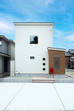 シンプルでモダンなデザインの住宅外観。白を基調にした外壁と木目調のアクセントが調和し、美しいファサードを演出。