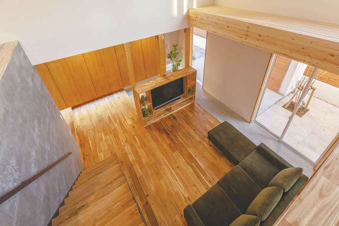 家の中で外の感覚になれる場所が、玄関からリビング、ダイニングまで延びる土間だ。生活スペースを取り囲むこの空間が、家の中と外の境界を柔らかくぼかし、中と外の繋がりをいっそう強めている。土間部分の天井は格子状になっているので、2階からの自然光が、まるで木漏れ日のように優しく降り注ぐ。