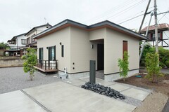 シンプルでモダンな平屋建ての外観。グレージュの外壁と木目調の軒天が美しく調和している。