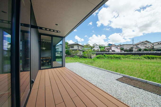 リビング、和室とフラットにつながるウッドデッキ。目の前にのどかな田園風景が広がり、縁側のようにくつろげる。深い軒があるので、強い日差しを遮りながらBBQや子どもプールを楽しむことができる