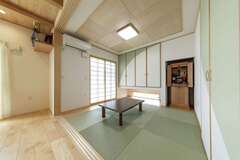 和室の建具は戸袋に収まり、リビングとバリアフリーでつながる。吊り収納と地窓が機能性と明るさを両立させた