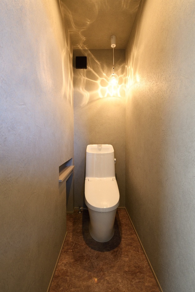 モダンなデザインのトイレ空間。暖かみのある照明で、シンプルながらもリラックスできる雰囲気が漂う