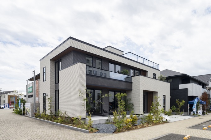 モダンスタイルの二階建て住宅。直線的なフォルムとバルコニーが印象的で、周囲の環境に溶け込むデザインが特徴的である。