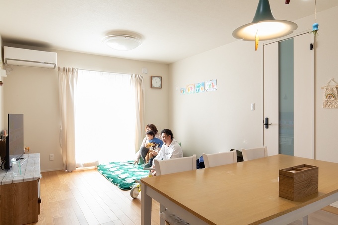 大きな窓から光が差し込むリビングダイニング。ナチュラルな内装で、家族がくつろげる空間が広がっている。