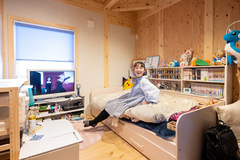 明るい色調の木材が印象的な子ども部屋。ベッドとテレビが配置され、遊びとリラックスの両方を楽しめる快適な空間が広がっている。