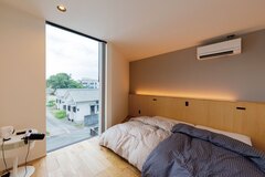 グレーの壁、間接照明、ピクチャーウインドウが特徴の主寝室【TENアーキテクツ一級建築士事務所】