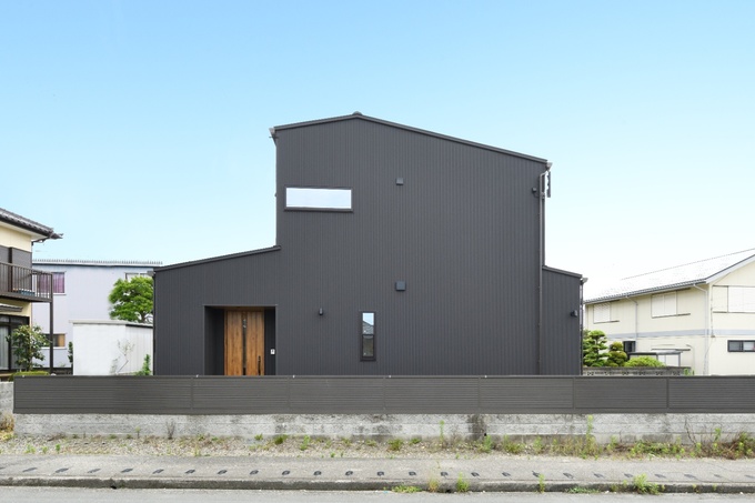 個性的なフォルムの一戸建て住宅の外観。シックな色合いが目を引き、周囲との調和を大切にした設計