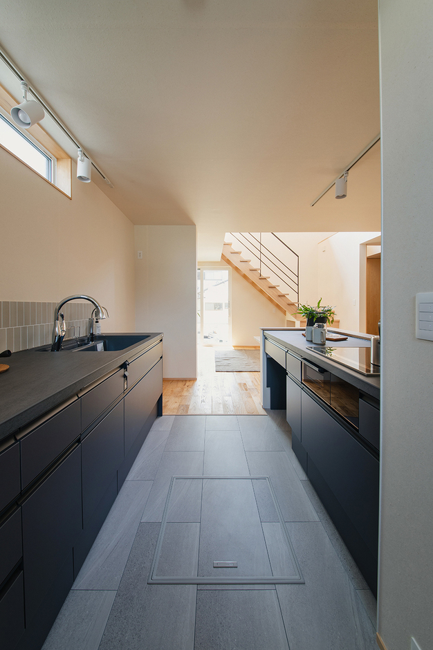 黒いキッチンにグレーのフロアタイルを組み合わせ、スタイリッシュに演出したキッチンスペース。床がフロアタイルなので、ワンちゃんたちが水を飲んでこぼしてもサッと拭き取れる