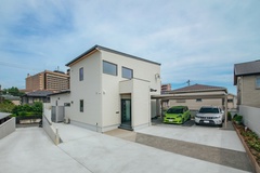 モダンなデザインの住宅外観。シンプルな配色で統一され、広々とした駐車スペースが確保されている。