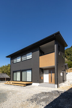 モダンなデザインの二階建て住宅の外観。ダークカラーの外壁にウッド調のアクセントが美しく調和している。【トキワハウス デザイン アンド ビルド（常盤工業）】