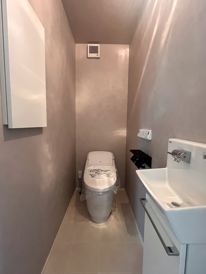 グレージュ系の壁でまとめたトイレは、やわらかく落ち着いた印象。手洗い器も備え、使いやすさにも配慮されています。