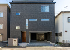 22坪の土地に完成した木造三階建て。1階はインナーガレージ付きで、雨に濡れることなく玄関までアクセスできる。ブラックの外壁が住宅街の中で存在感を発揮。すっきりとした外観をよりおしゃれに見せている