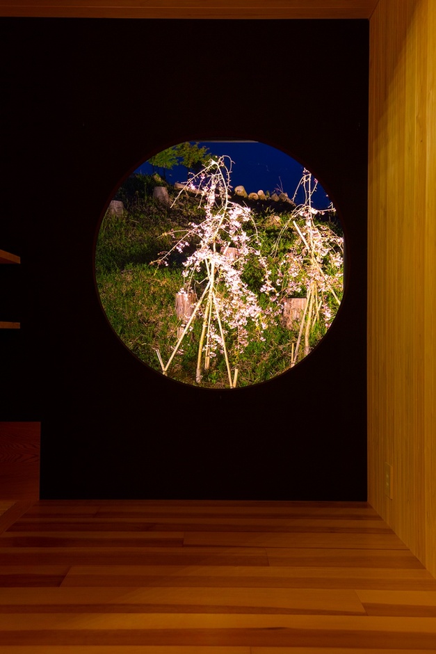 和室の円形の窓が特徴的なスペース。夜景の桜を望むことができ、落ち着いた雰囲気を演出している。自然と調和した空間は、居心地の良さを提供する。