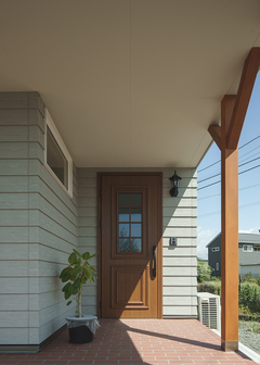 木目調の玄関ドアが家の雰囲気によく似合う。雨の時には深い軒が傘の代わりになり、スムーズに出入りできる