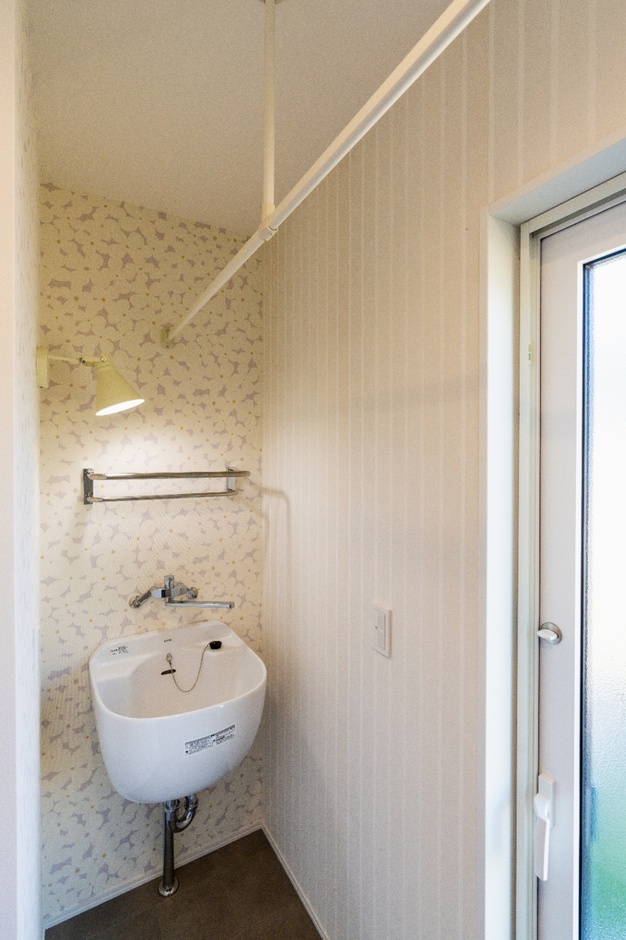 ランドリーパイプにスロップシンク。可愛らしいクロスに囲まれた家事が捗るスペース。