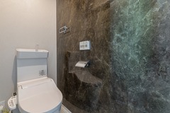 高級感のある石目調の壁が印象的なトイレ空間。シンプルでありながら洗練されたデザインで、落ち着いた雰囲気を持つ。【サンジョーホーム】