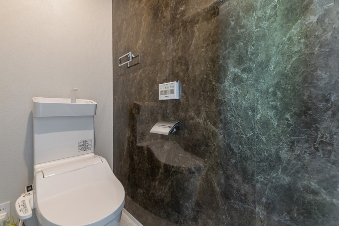 高級感のある石目調の壁が印象的なトイレ空間。シンプルでありながら洗練されたデザインで、落ち着いた雰囲気を持つ。