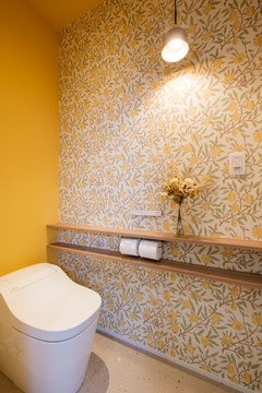 黄色い花柄のクロスと可愛らしい照明が特徴のトイレ。自然モチーフのデザインが施され、落ち着いた雰囲気を演出する