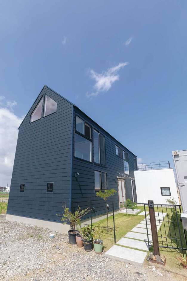 陶器のような風合いと波形デザインが調和した外観が住まい手の個性を引き出す。敷地内にはコンテナハウスもある