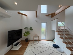 明るい光が差し込む開放的なLDK空間。テレビ、観葉植物、階段が配置され、シンプルでモダンなインテリアデザインが特徴。【タカオ設計】