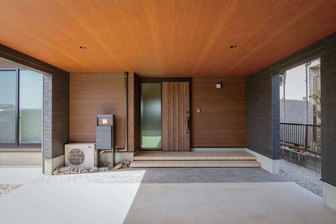 ガレージの内側に設けた玄関。玄関ポーチやガレージの天井には木目を採用し、ホテルのエントランスのような重厚感を演出。雨天でも雨にぬれずに車と家を行き来できるので、子育て中のお二人も大助かり！