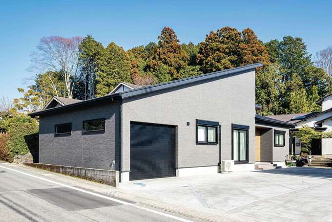 スタイリッシュな片流れの外観フォルム。平屋のように見えるグレージュの二階建てが青空と緑の山々に美しく映える。インナーガレージからパントリーに直結する買い物動線も重宝している