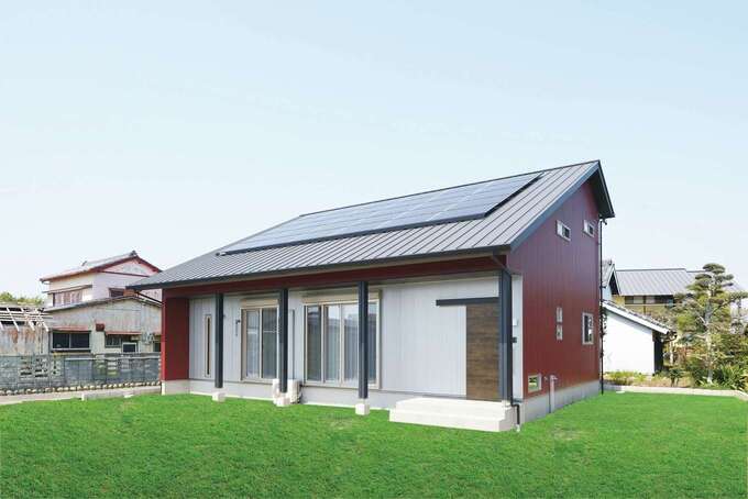 大屋根がインパクトを放つ平屋風の2階建て。ワインレッド×シルバーの外壁が個性的